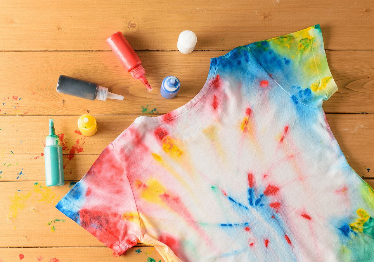 Tie-dye T-shirt with vibrant red, blue, and yellow designs on a wooden table.